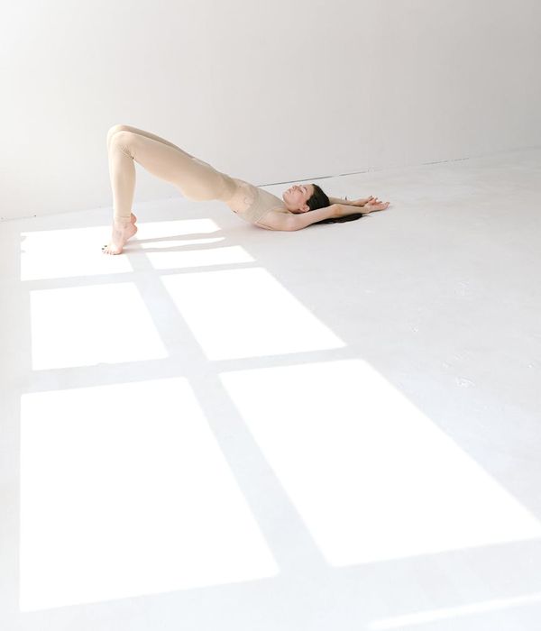Woman performing a gentle stretching yoga pose in a bright studio.